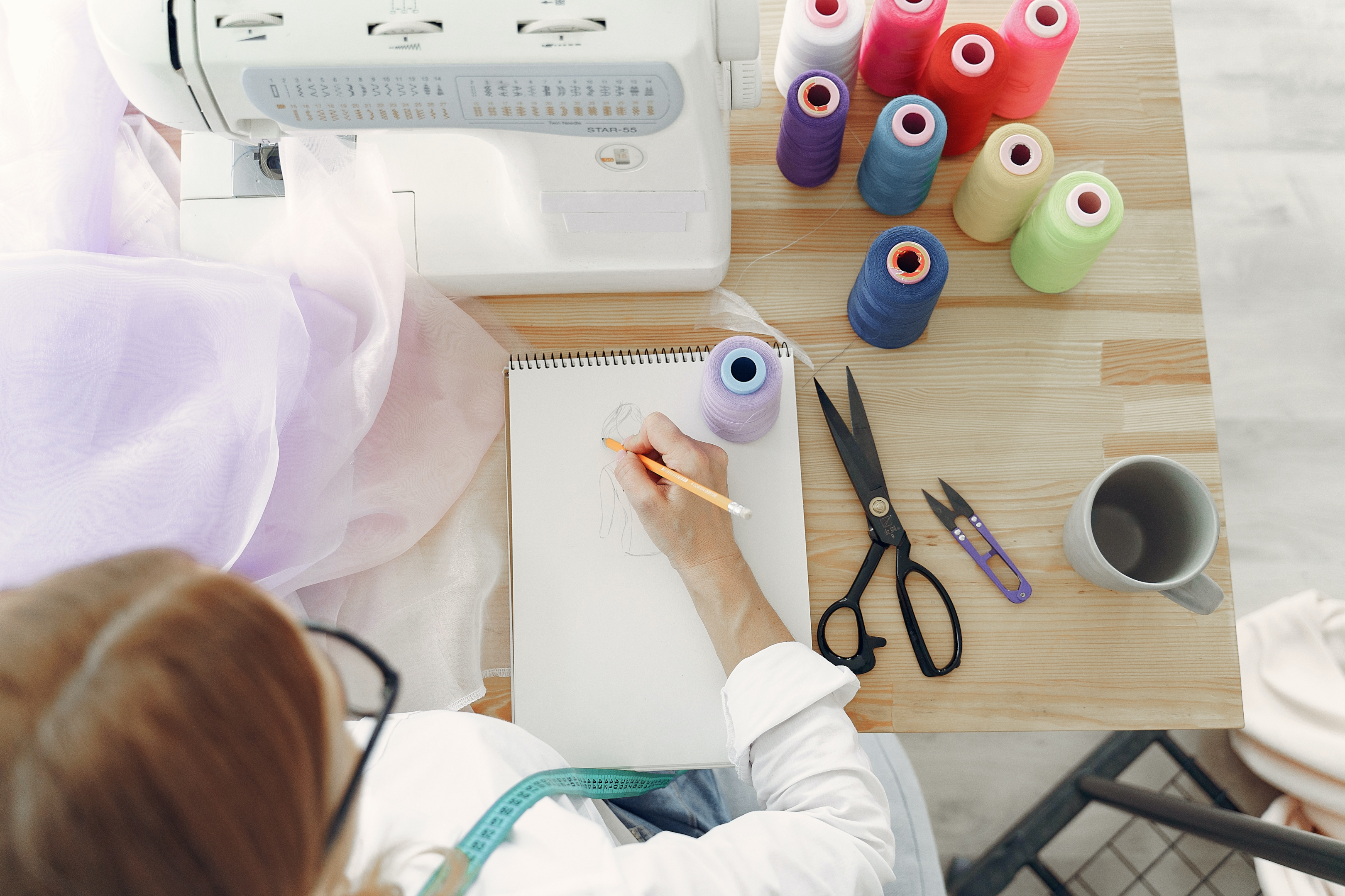 Designer sketching next to a sewing machine.